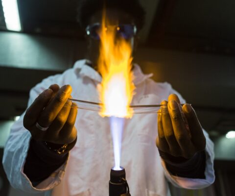Stagiaire en cours de fabrication d'un tube à essai au chalumeau dans le cadre de son CAP Souffleur de verre option verrerie scientifique.