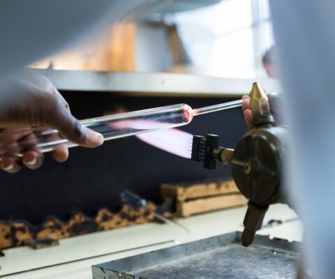 Stagiaire apprenant en atelier à transformer le verre au chalumeau.